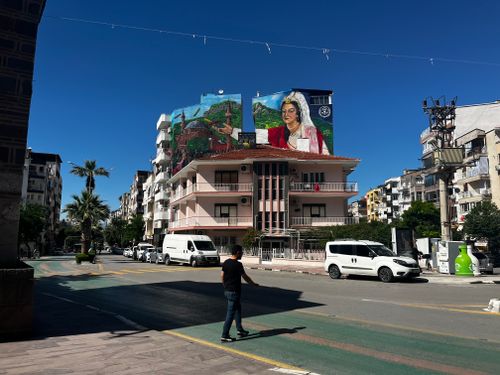 Free City street view with a vibrant mural on a building wall under a clear blue sky. Stock Photo