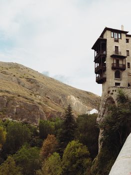Iconic Hanging Houses of Cuenca, Spain, perched on a cliffside amid lush greenery.