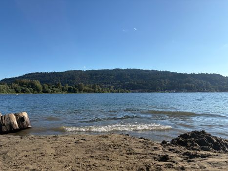 Beautiful lake view with gentle waves and serene forest background, ideal for nature lovers.