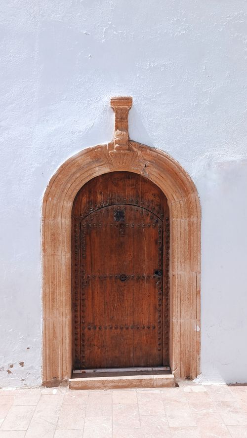 Free An ornate wooden door with a stone arch in Tangier, Morocco. Ideal for cultural and travel visuals. Stock Photo
