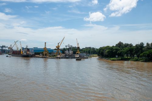 Free Wide view of a bustling industrial river port with cranes and water reflecting a sunny sky. Stock Photo