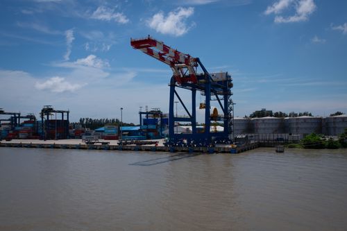Free View of a busy industrial port with cargo cranes and containers under a clear blue sky. Stock Photo