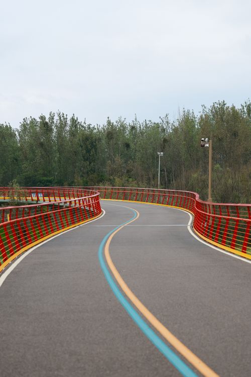 Free Empty road with red guardrails and lush trees, perfect for travel and outdoor concepts. Stock Photo