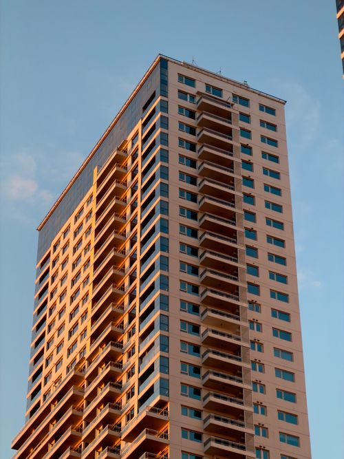 Free A stunning view of a modern high-rise building illuminated by sunset light. Stock Photo