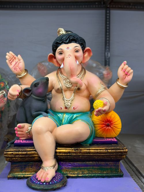 Free Brightly painted Ganesh idol with traditional elements, sitting with a mouse and holding a modak, symbolizing Hindu culture. Stock Photo