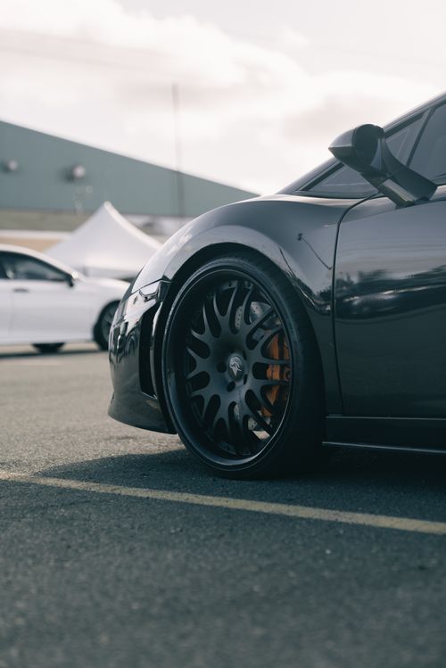 Free Detailed view of a luxury sports car wheel in a parking lot on a sunny day. Stock Photo