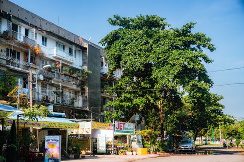Free A sunny street in Ho Chi Minh City showcasing residential apartments and a vibrant local market. Stock Photo