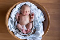 一个安详的新生婴儿舒适地窝在铺着软毯子的木篮里