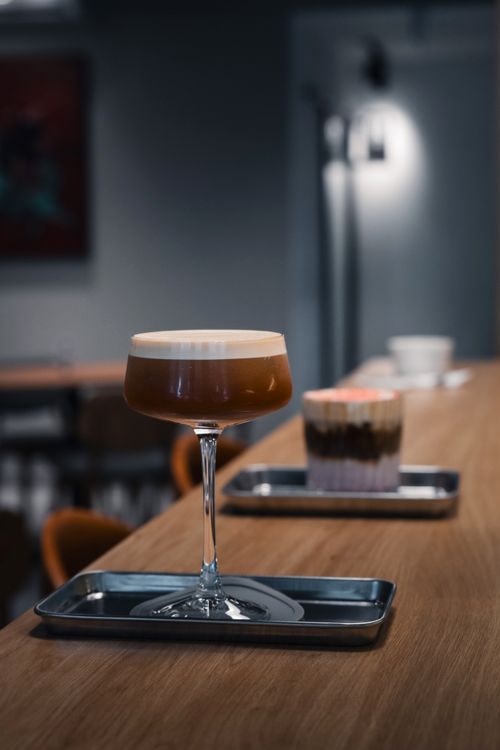 Free A sophisticated espresso martini served on a wooden bar in a modern cafe setting, perfect for an ambient evening. Stock Photo