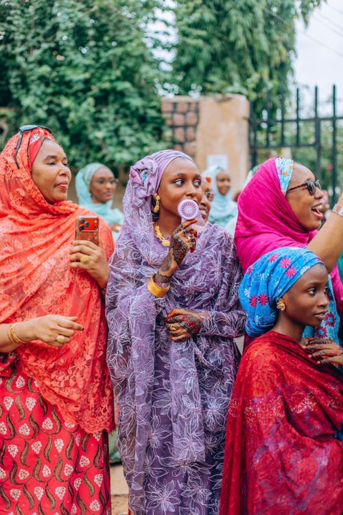 Free Group of women in vibrant traditional African attire enjoying an outdoor gathering. Stock Photo