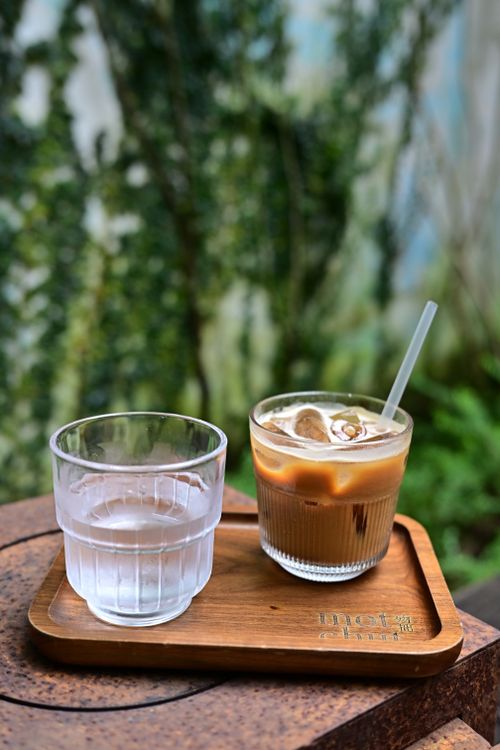 Free A refreshing iced coffee and water on a wooden tray in a vibrant outdoor setting. Stock Photo