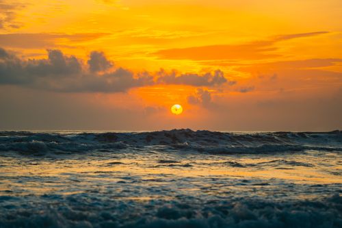 Free Breathtaking view of a vibrant sunset over crashing ocean waves, perfect for travel or nature themes. Stock Photo