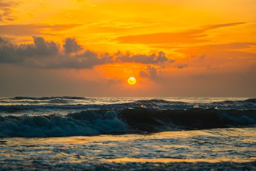 Free A stunning sunrise over the ocean with vibrant colors reflecting on the waves and clouds. Stock Photo