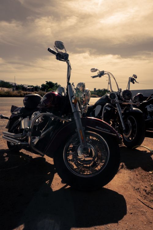 Free Parked Harley Davidson motorcycles under a warm sunset in La Paz, Mexico, perfect for travel enthusiasts. Stock Photo