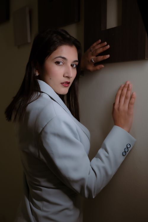 Free Portrait of a young woman in a white blazer posing indoors with a confident expression. Stock Photo