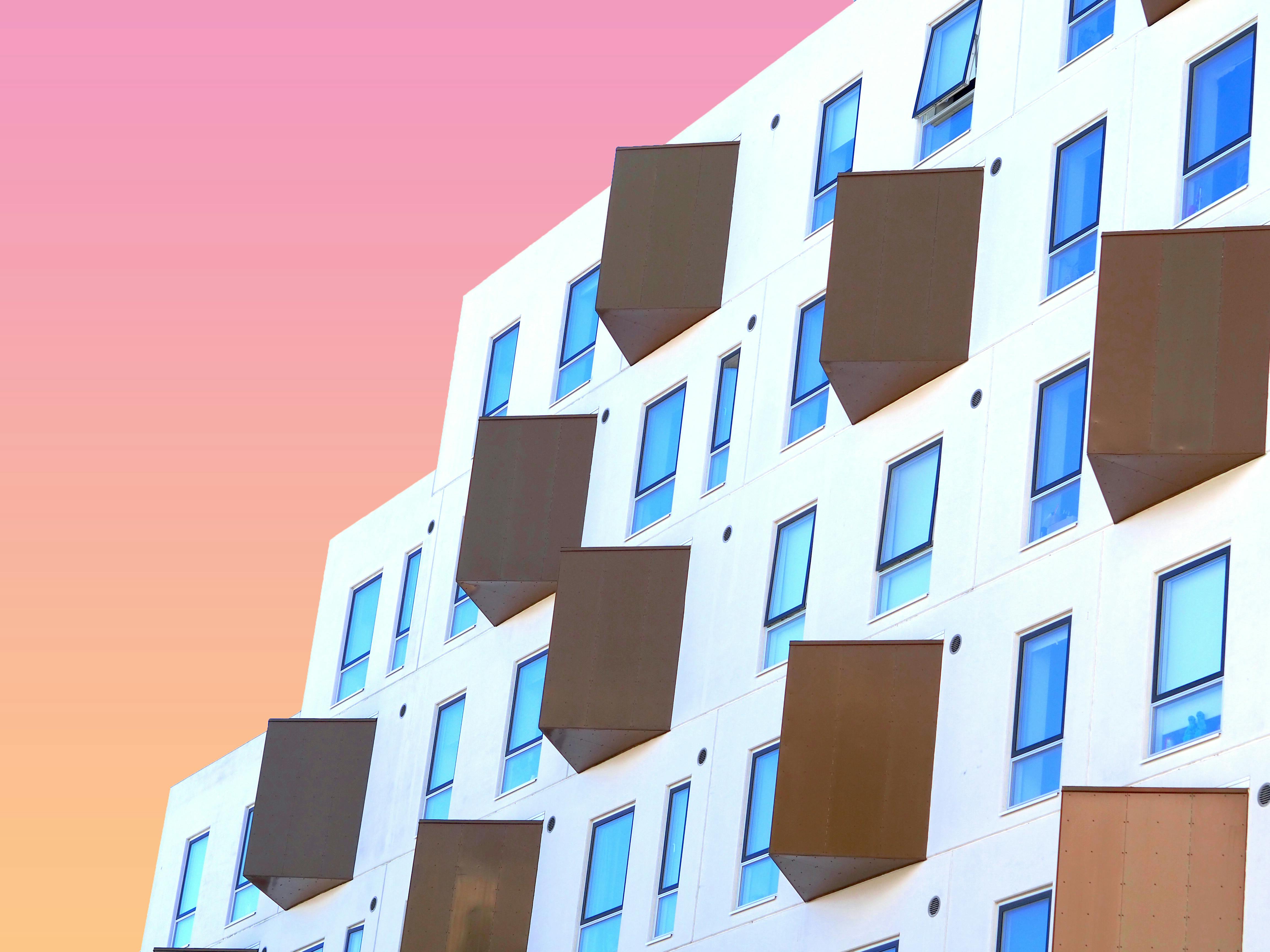 Contemporary building facade with unique windows in Odense, Denmark, under a pastel sky.