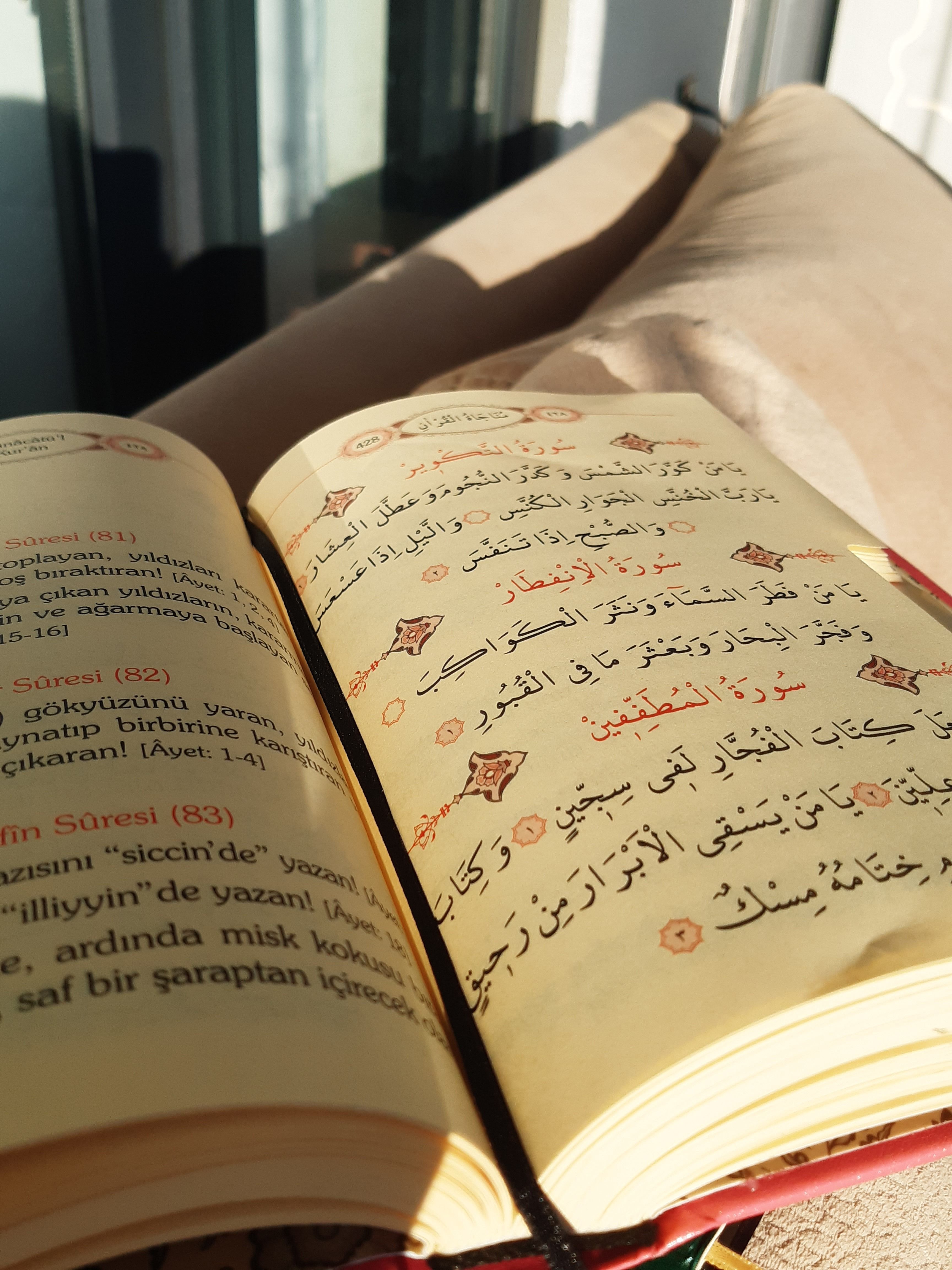 An open book with Arabic and Latin scripts illuminated by warm sunlight indoors.