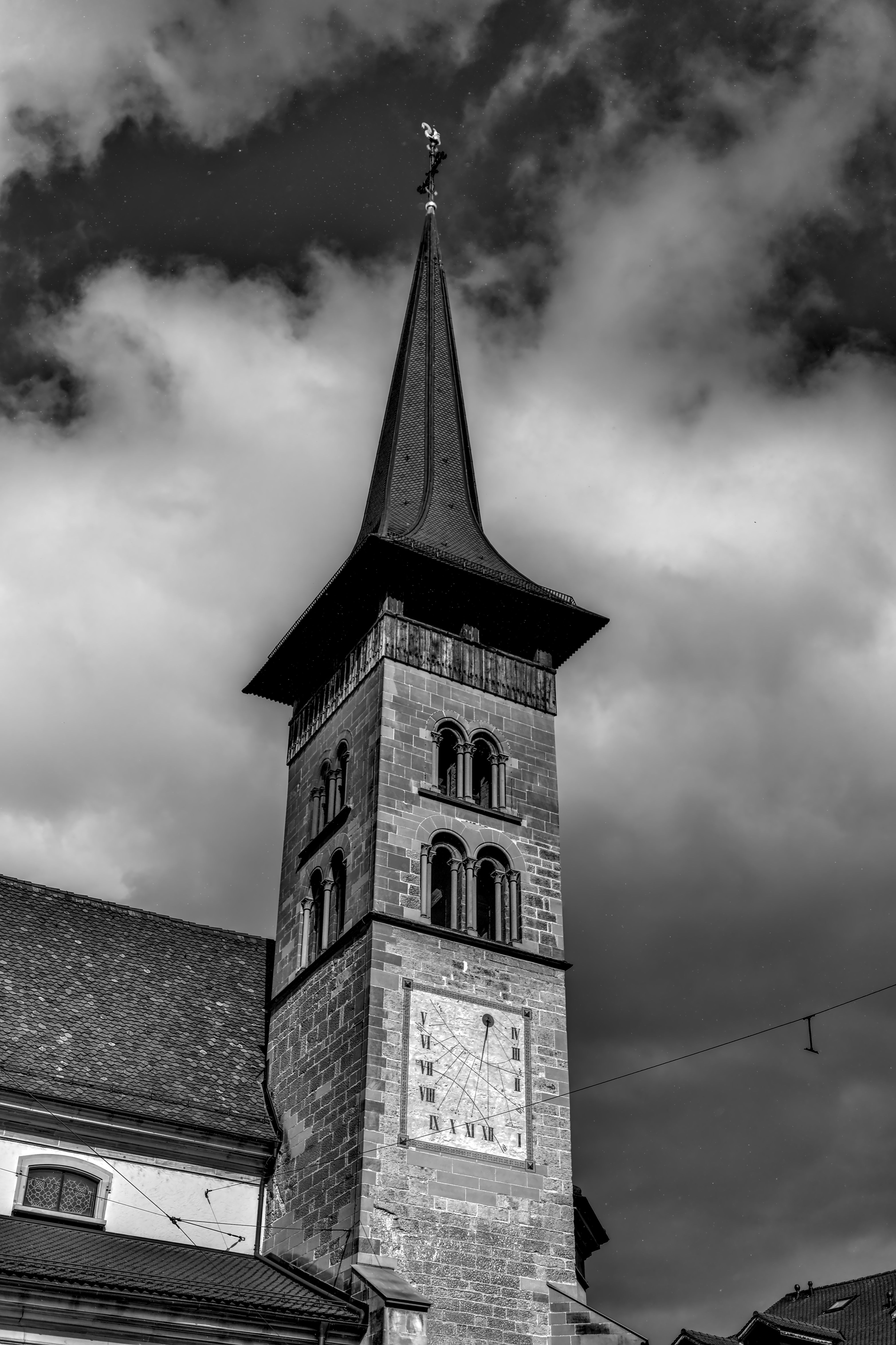 A striking black and white photo of a historic church tower with a clock, set against a dramatic cloudy sky.