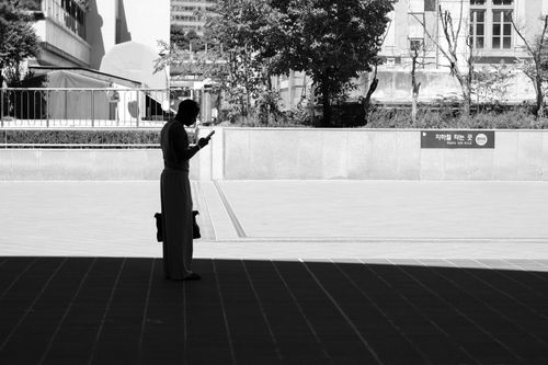 Free Black and white silhouette of a person using a smartphone in an urban outdoor setting. Stock Photo