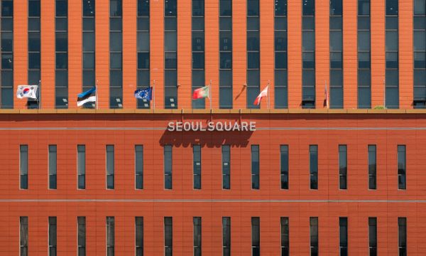 Red facade of Seoul Square with multiple international flags displayed.