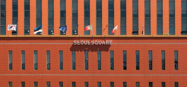 Red facade of Seoul Square with multiple international flags displayed.