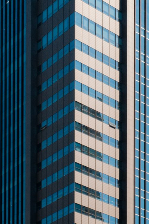 Free Modern high-rise building facade with reflective glass windows in urban setting. Stock Photo