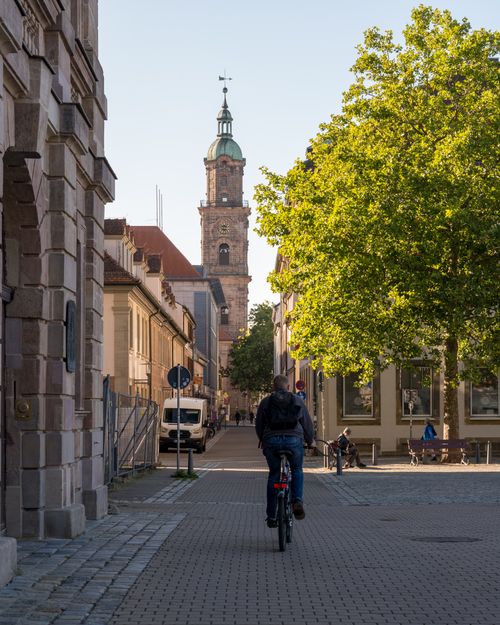 Free Bavarian city street featuring historic architecture, cobblestones, and a cyclist under a clear sky. Stock Photo