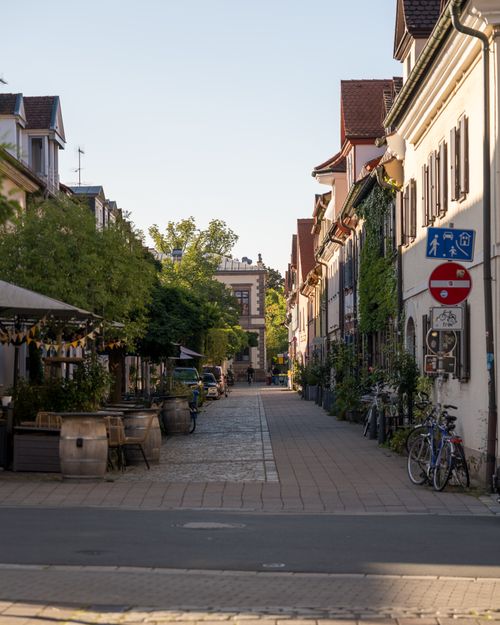 Free Explore a charming cobblestone street with old European architecture and vibrant greenery. Stock Photo
