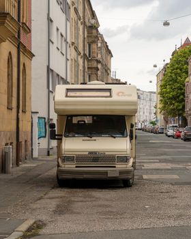 A vintage camper van parked on a picturesque cobblestone street in a European city.
