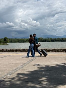 A couple strolls along Sukhna Lake in Chandigarh under dramatic skies.