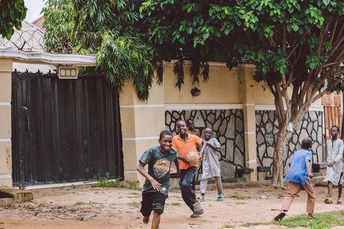 Free Kids enjoy a lively game of soccer in a residential backyard, filled with joy and energy. Stock Photo
