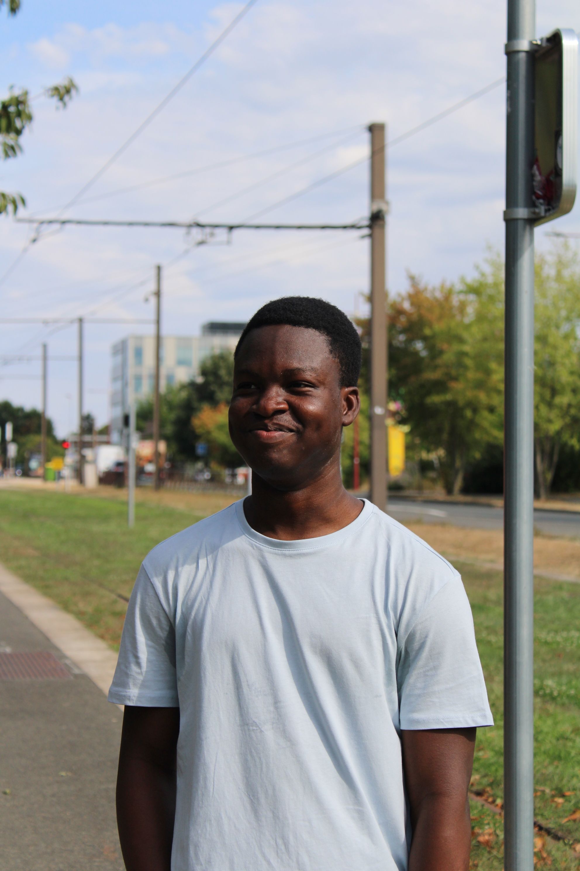 A cheerful man enjoys a sunny day in an urban park, showcasing relaxed happiness.