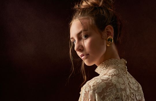 Portrait of a young woman with elegant hairstyle and lace dress, showcasing vintage earrings.