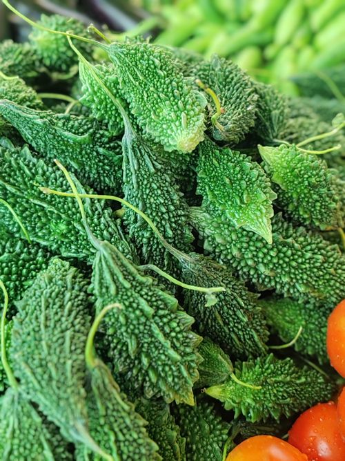 Free Close-up of fresh bitter melon with vibrant green color at a market stall. Stock Photo