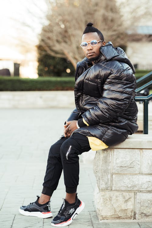 Man In Black Bubble Jacket And Black Pants Sitting 