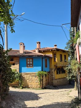 Colorful Ottoman-style houses in a cobblestone alley under the bright blue sky, exuding historic charm.