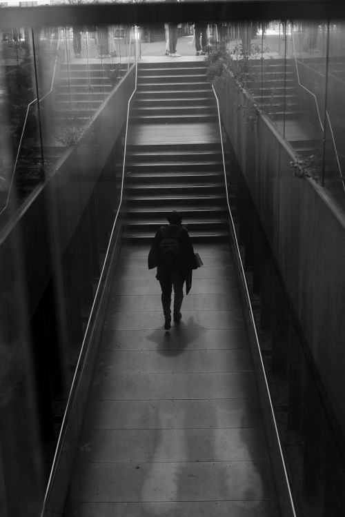Free A silhouetted person walks up a modern urban staircase, captured in a black and white minimalist style. Stock Photo