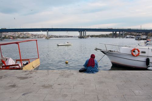 Free A serene moment by the Golden Horn in Istanbul with a woman in a hijab sitting near boats. Stock Photo
