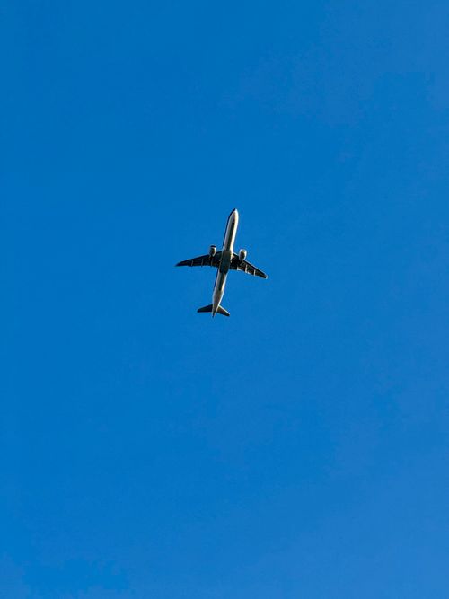 Free A lone airplane flying high in the sky against a vibrant blue backdrop. Stock Photo