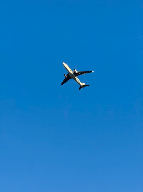 Free Airplane flying against a vivid blue sky, symbolizing travel and aviation. Stock Photo