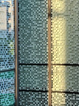 Intricate glass facade with modern geometric patterns lit by sunlight.