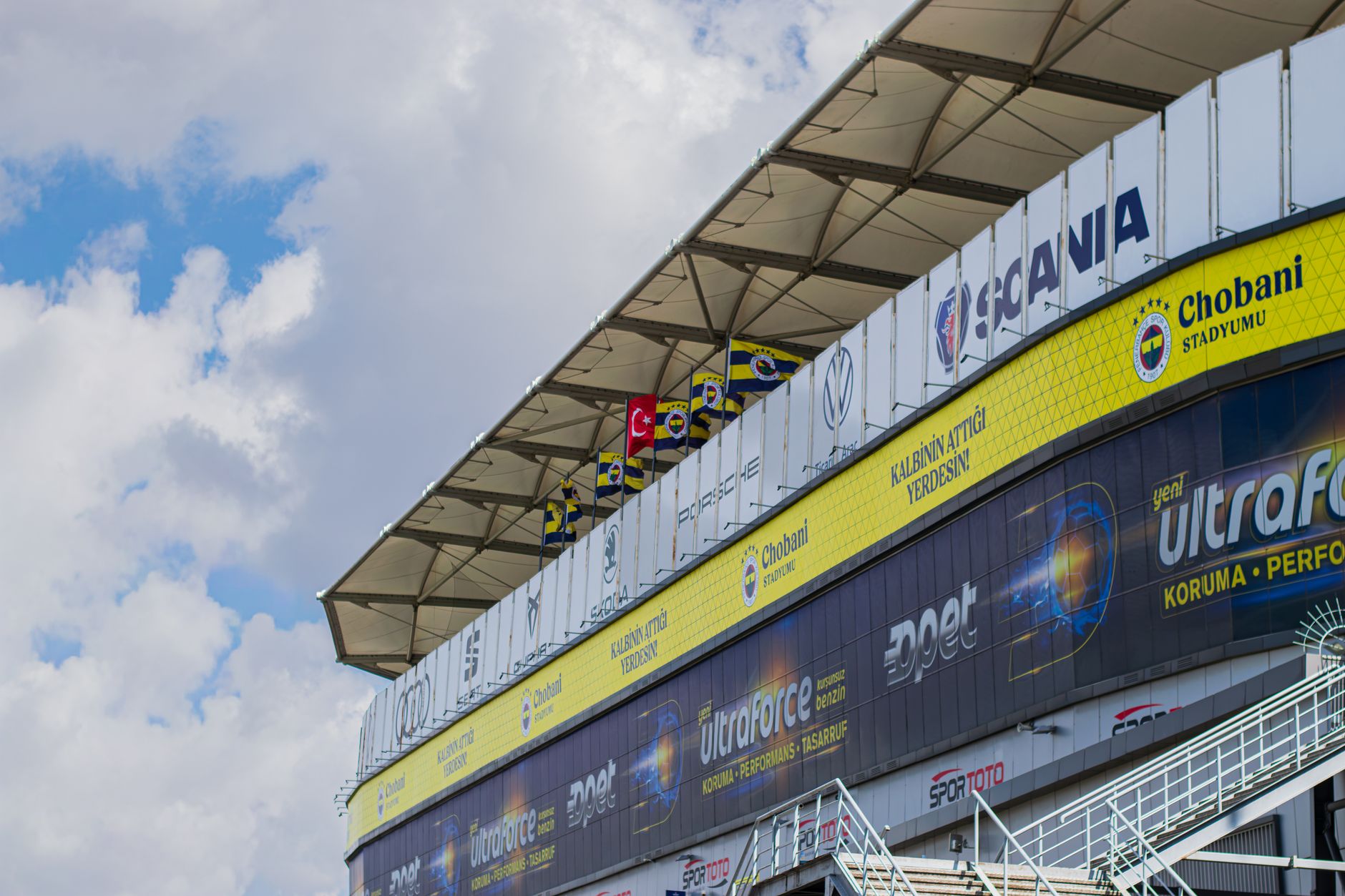 A stadium facade featuring Chobani and sports brand ads with a Turkish flag.