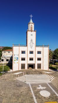 Aerial view of a traditional church with large cross and religious iconography against clear blue sky.