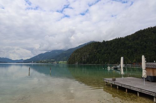 Free A serene landscape featuring a calm lake, lush mountains, and a wooden pier in Austria. Stock Photo
