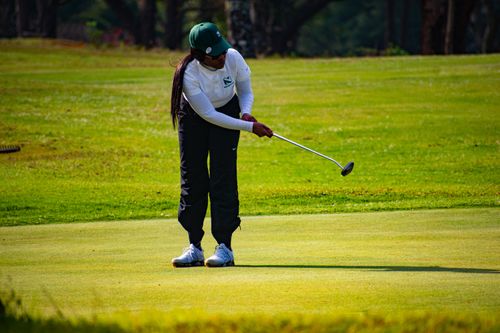 Free A woman focuses on her golf swing on a green course in Eswatini, showcasing concentration and skill. Stock Photo