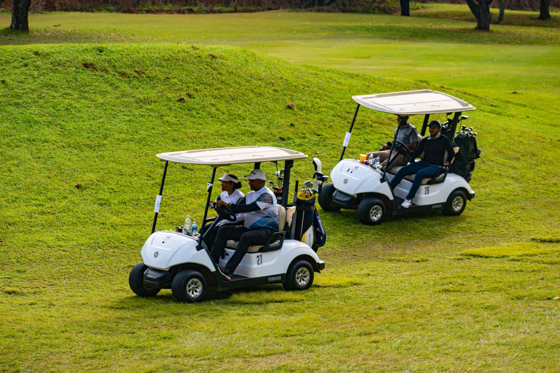 Golfers enjoying a day on the course in Piggs Peak, Eswatini, riding in golf carts.
