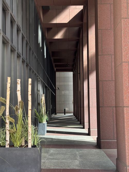 Free A view through a modern architectural corridor with plants and light creating geometric shadows. Stock Photo
