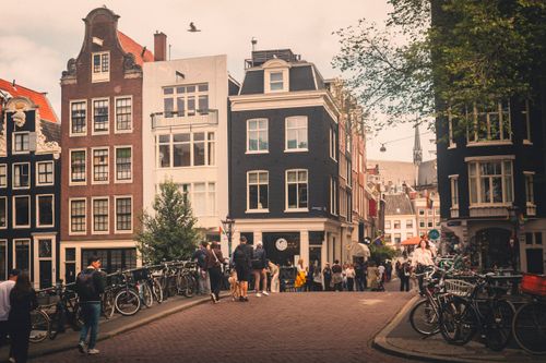 Free A vibrant scene of historic Amsterdam architecture and lively street life on a sunny day. Stock Photo