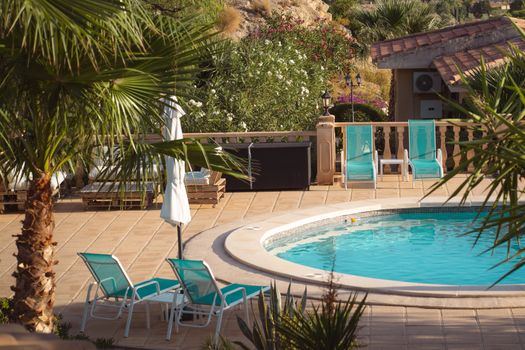 Charming pool area with sun loungers and tropical plants ideal for vacations and relaxation.