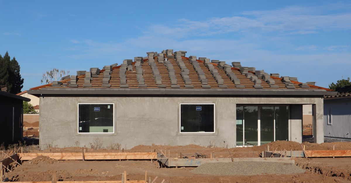 A new home under construction featuring a tiled roof and unfinished exterior.